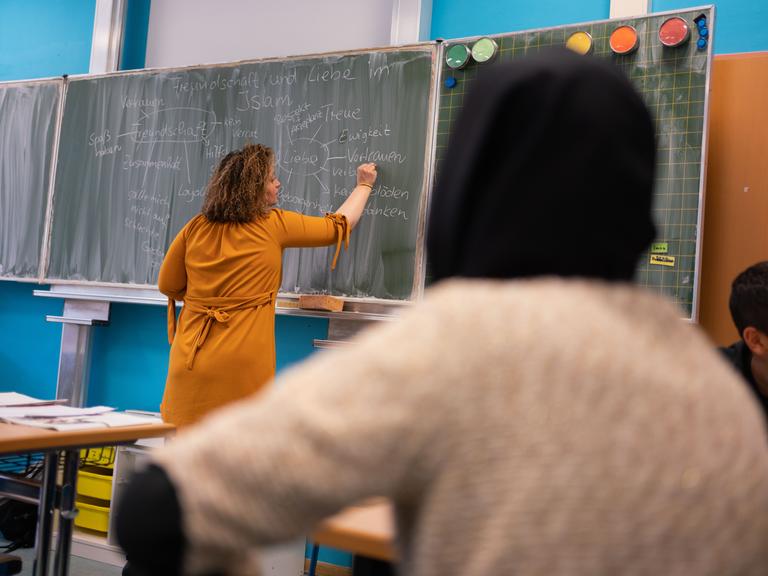 Die Lehrerin Nurdagül Ceri schreibt beim Islamunterricht in der Frankfurter Ernst-Reuter-Schule mit Schülern einer siebten Klasse Sätze an die Tafel.