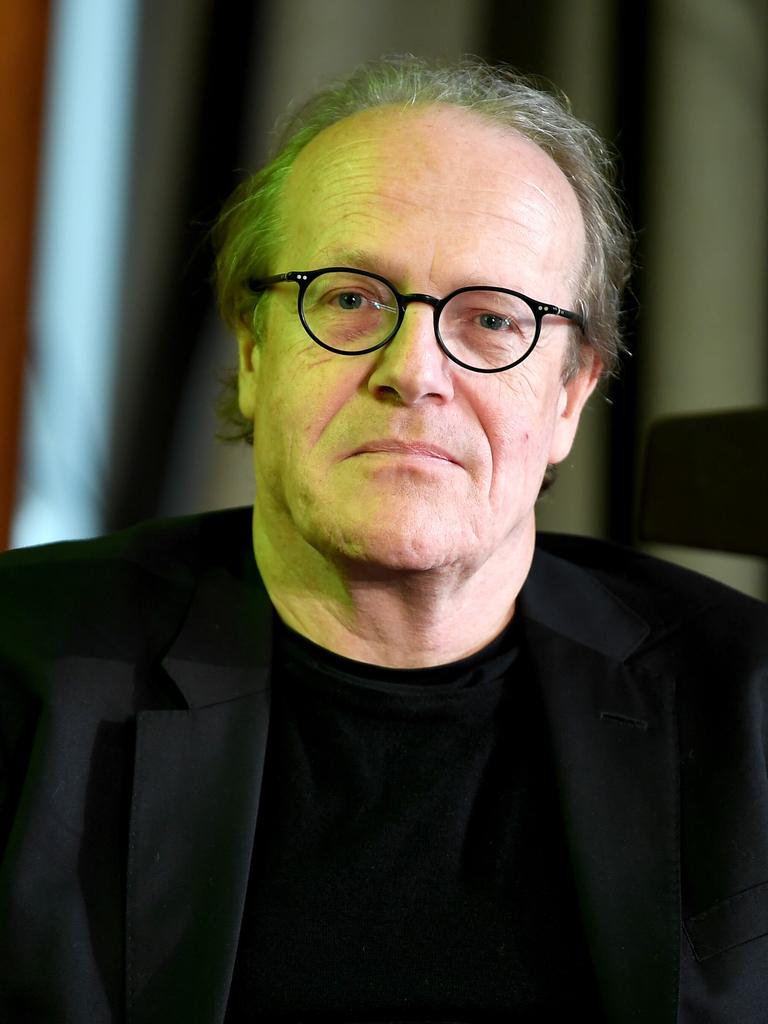 Thomas Flierl schaut direkt in die Kamera. Er trägt ein schwarzes Sakko und eine runde schwarze Brille.