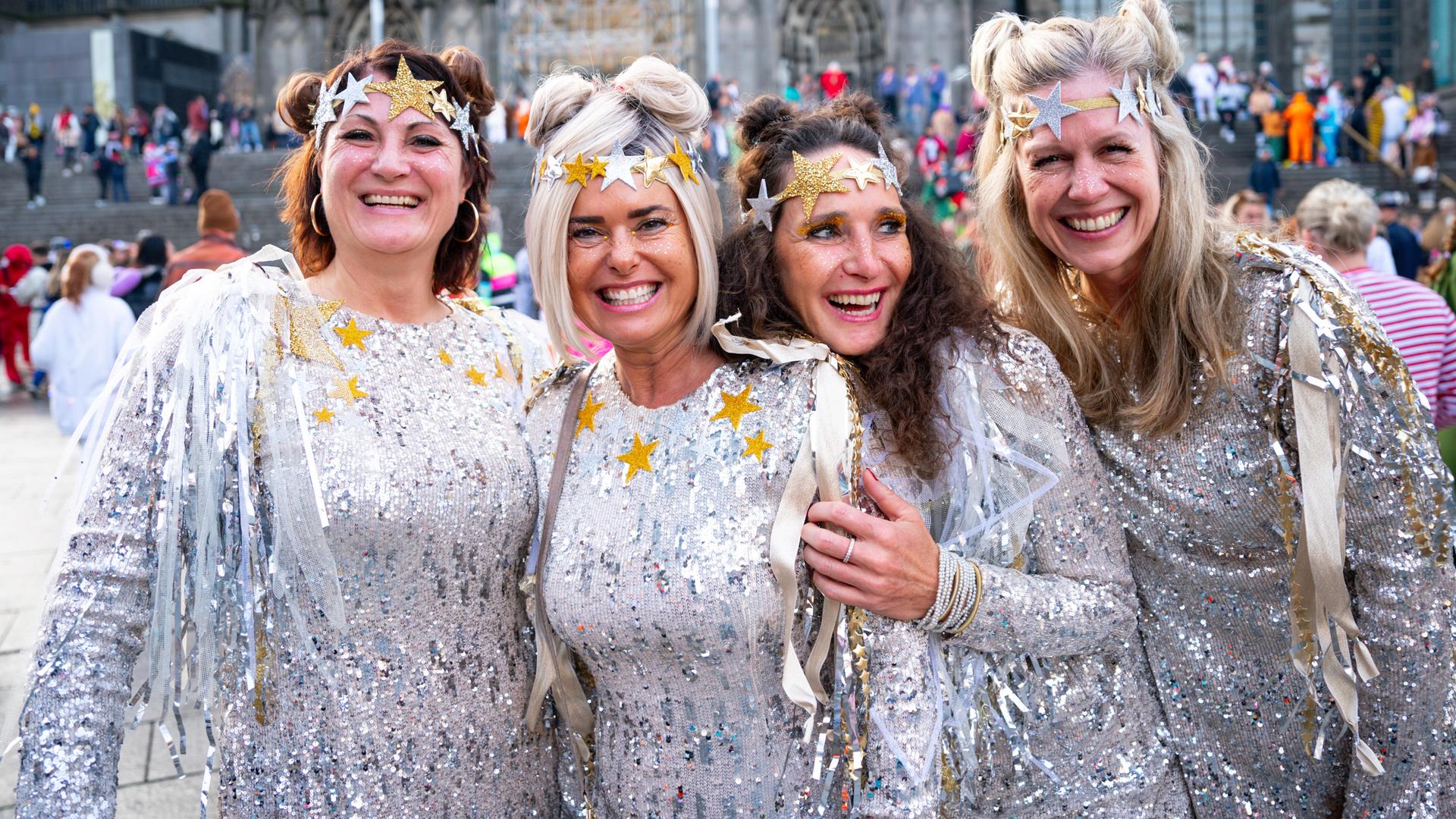 Vier verkleidete Frauen stehen nebeneinander und lachen.