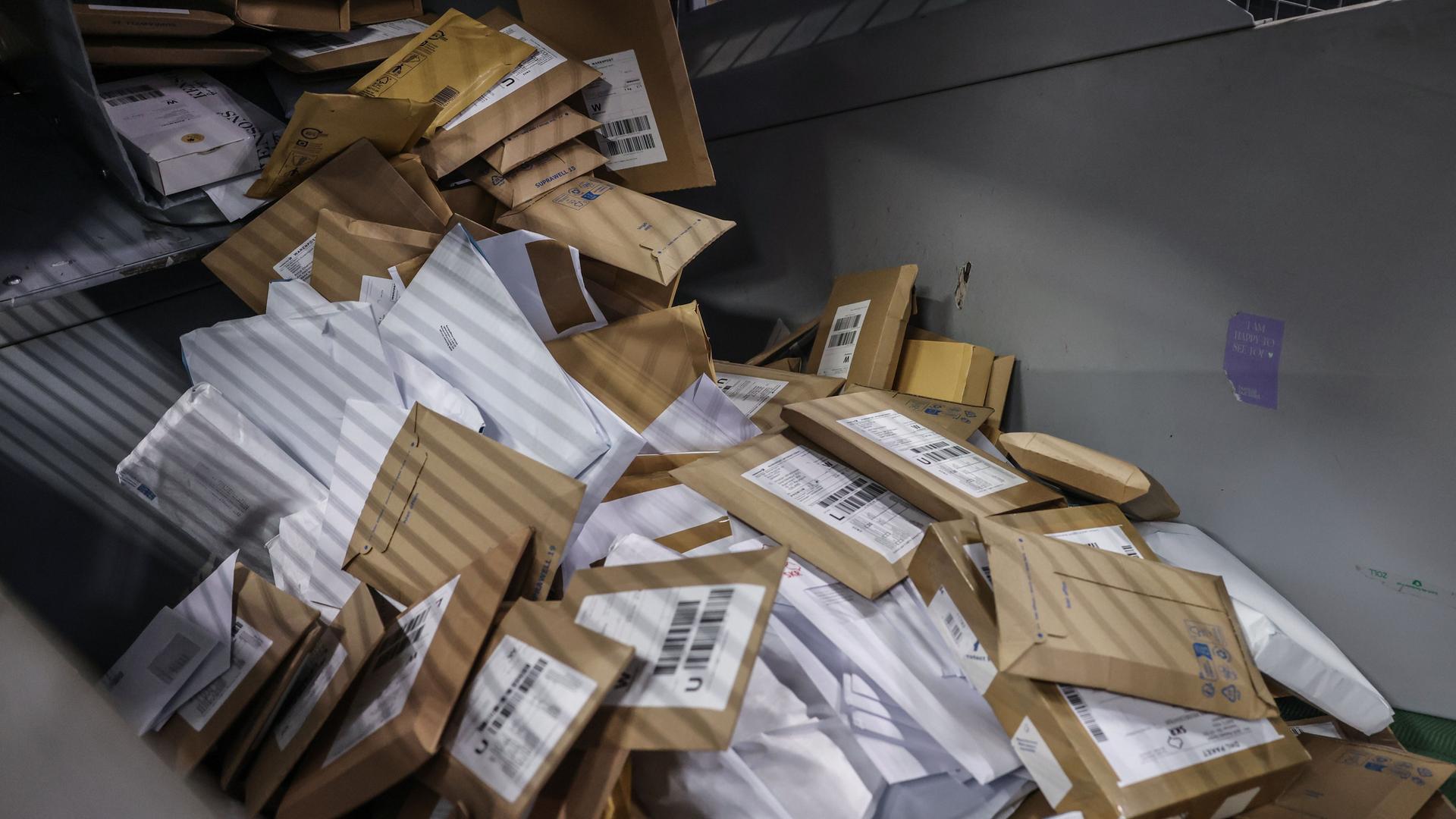 Briefsendungen fallen im Verteilzentrum der Deutschen Post DHL in eine Sortiermaschine.