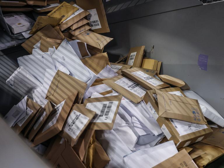 Briefsendungen fallen im Verteilzentrum der Deutschen Post DHL in eine Sortiermaschine.
