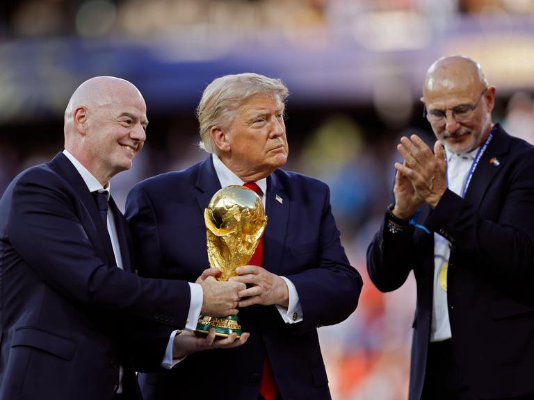 Gianni Infantino und Donald Trump halten bei der Siegerehrung der FIFA WM 2026 den Pokal in Händen, abseits steht der Trainer der siegreichen spanischen Nationalmannschaft Luis de la Fuente.