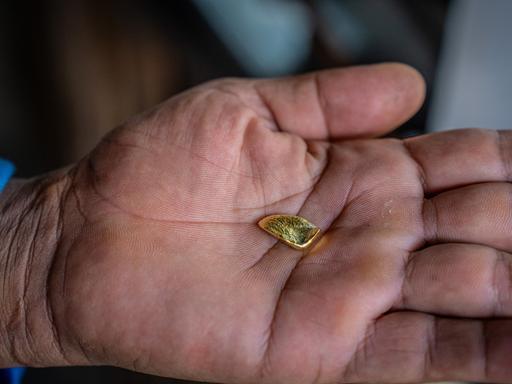 Ein Stück Gold in einer Handfläche eines Menschen