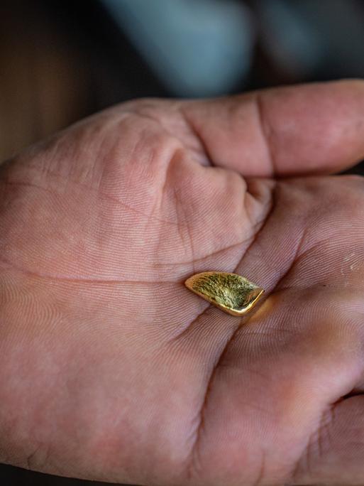 Ein Stück Gold in einer Handfläche eines Menschen