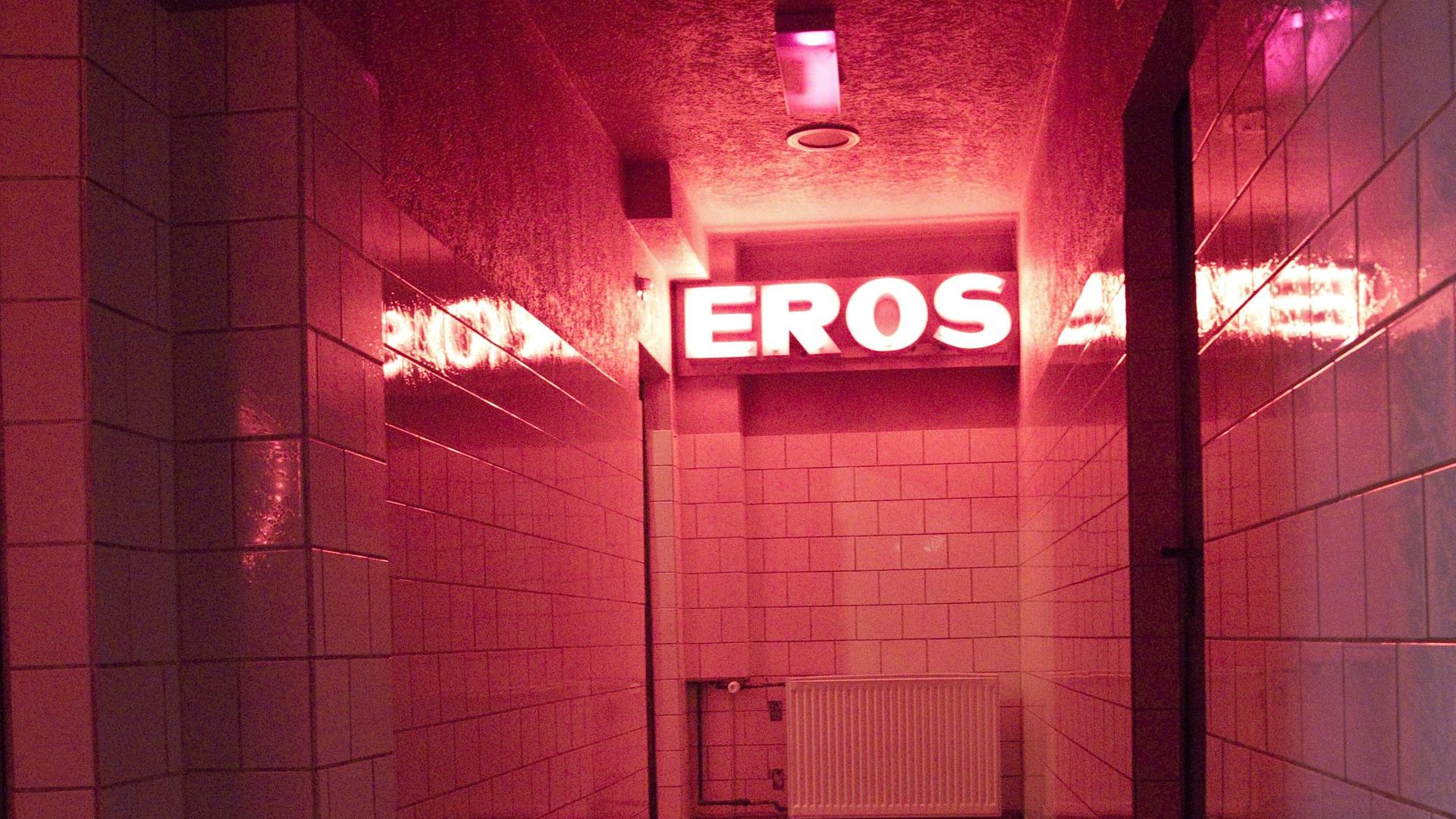Symbolbild Prostitution: Der Gang in einem Bordell. An der Wand hängt eine Lichtinstallation mit dem Schriftzug Eros.