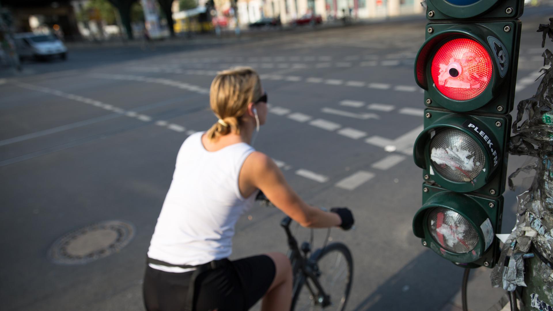 Eine Radfahrerin fährt über eine rote Ampel. Die Aufnahme zeigt die Bewegung, es ist ein verwischtes Foto.