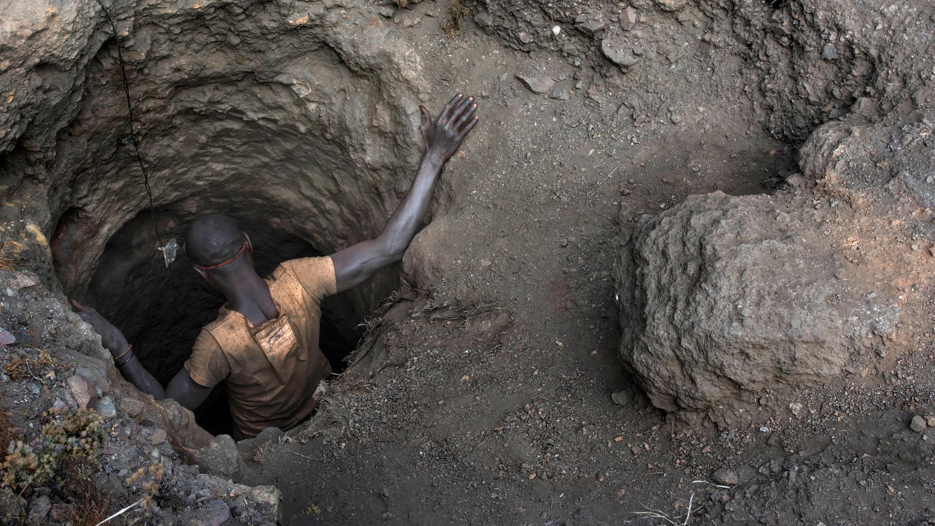 Ein Arbeiter beim Einstieg in ein kleines Loch einer Kupfer- und Kobaltmine in Kawama, Demokratische Republik Kongo.