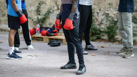 Mehrere Jugendliche mit Boxhandschuhen stehen auf einem Hof.