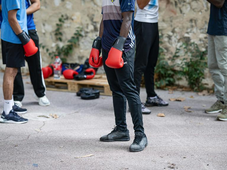 Mehrere Jugendliche mit Boxhandschuhen stehen auf einem Hof.