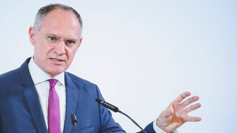 Österreichs Innenminister Gerhard Karner (ÖVP) steht an einem Pult vor einer weißen Wand und spricht.