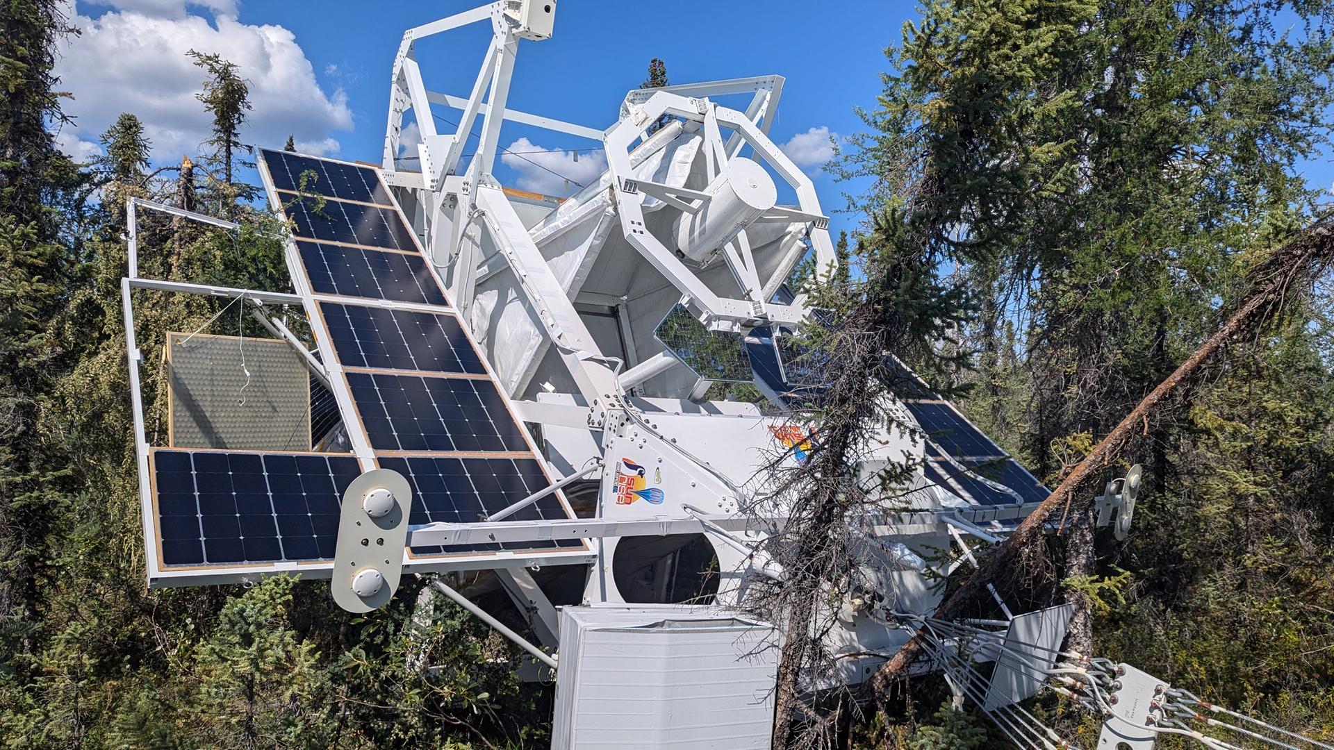 Das Sonnenteleskop "Sunrise III" liegt nach der Landung zwischen Bäumen in der Wildnis. An dem Gerät sind zudem seitlich angebrachte Solarmodule zu sehen. Das Sonnenteleskop "Sunrise III" liegt nach der Landung zwischen Bäumen in der Wildnis. An dem Gerät sind zudem seitlich angebrachte Solarmodule zu sehen.