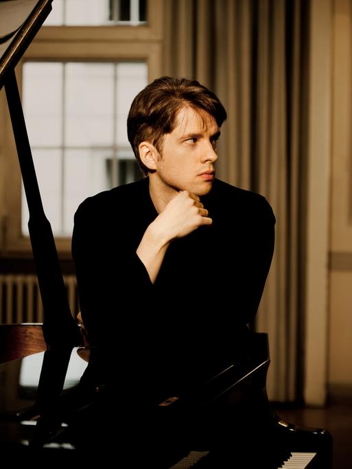 Der Pianist Severin von Eckardstein hinter einem schwarzen Flügel.