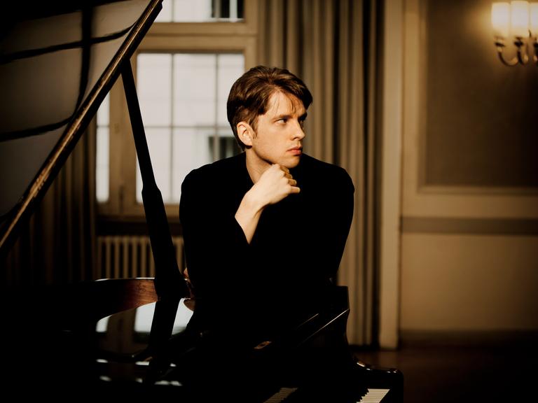 Der Pianist Severin von Eckardstein hinter einem schwarzen Flügel.
