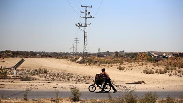 Ein palästinensischer Junge schiebt am 3. Juli 2024 sein mit Brennholz beladenes Fahrrad auf der Salah-El-Din-Straße in Deir al-Balah im Gazastreifen. 