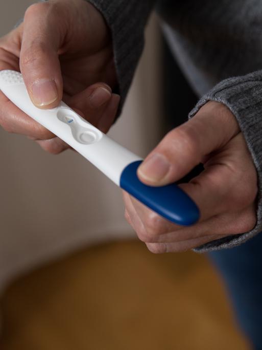 Eine Nahaufnahme von Händen, die einen negativen Schwangerschaftstest halten.