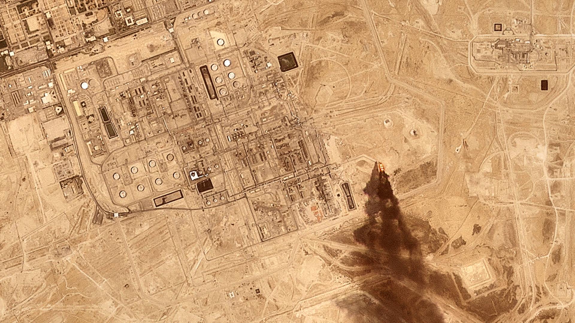 Ein Satellitenbild zeigt eine Raffinerie des saudischen Ölkonzerns Aramco, an deren Rand eine große Rauchwolke nach einem Drohnenangriff aufsteigt.