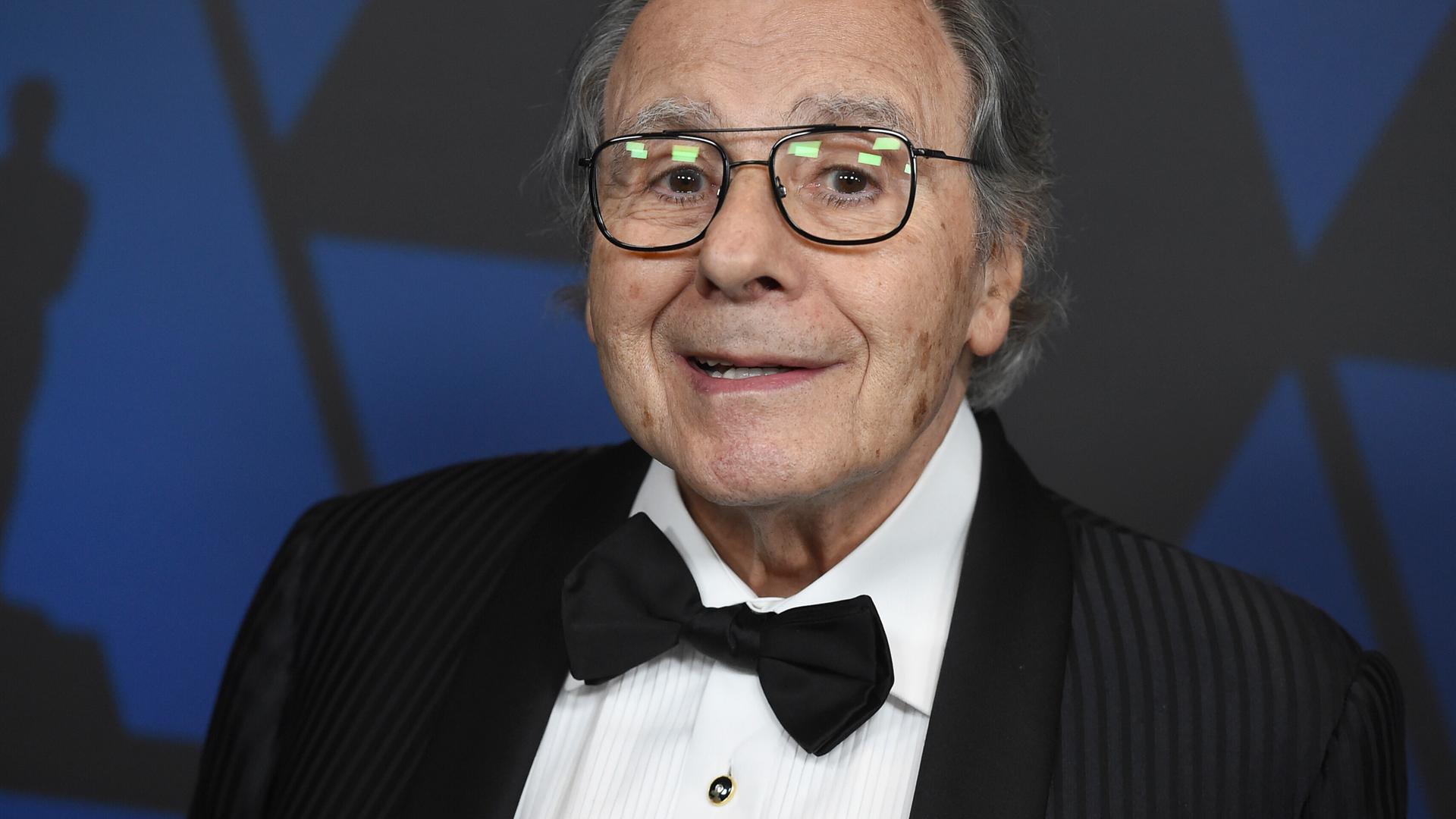 Portrait von Lalo Schifrin, er trägt eine schwarze Fliege, ein schwarzes Sakko und schaut freundlich in die Kamera.