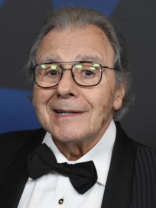 Portrait von Lalo Schifrin, er trägt eine schwarze Fliege, ein schwarzes Sakko und schaut freundlich in die Kamera.