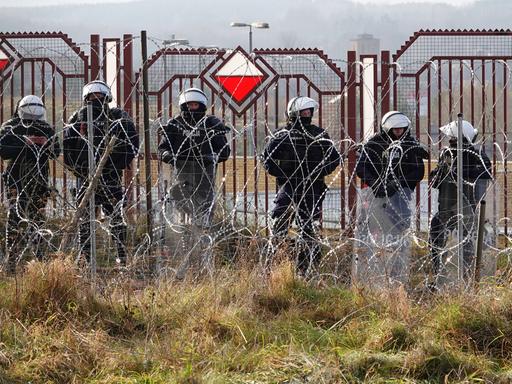 Polnische Sicherheitskräfte stehen an der Grenze hinter Stacheldraht.