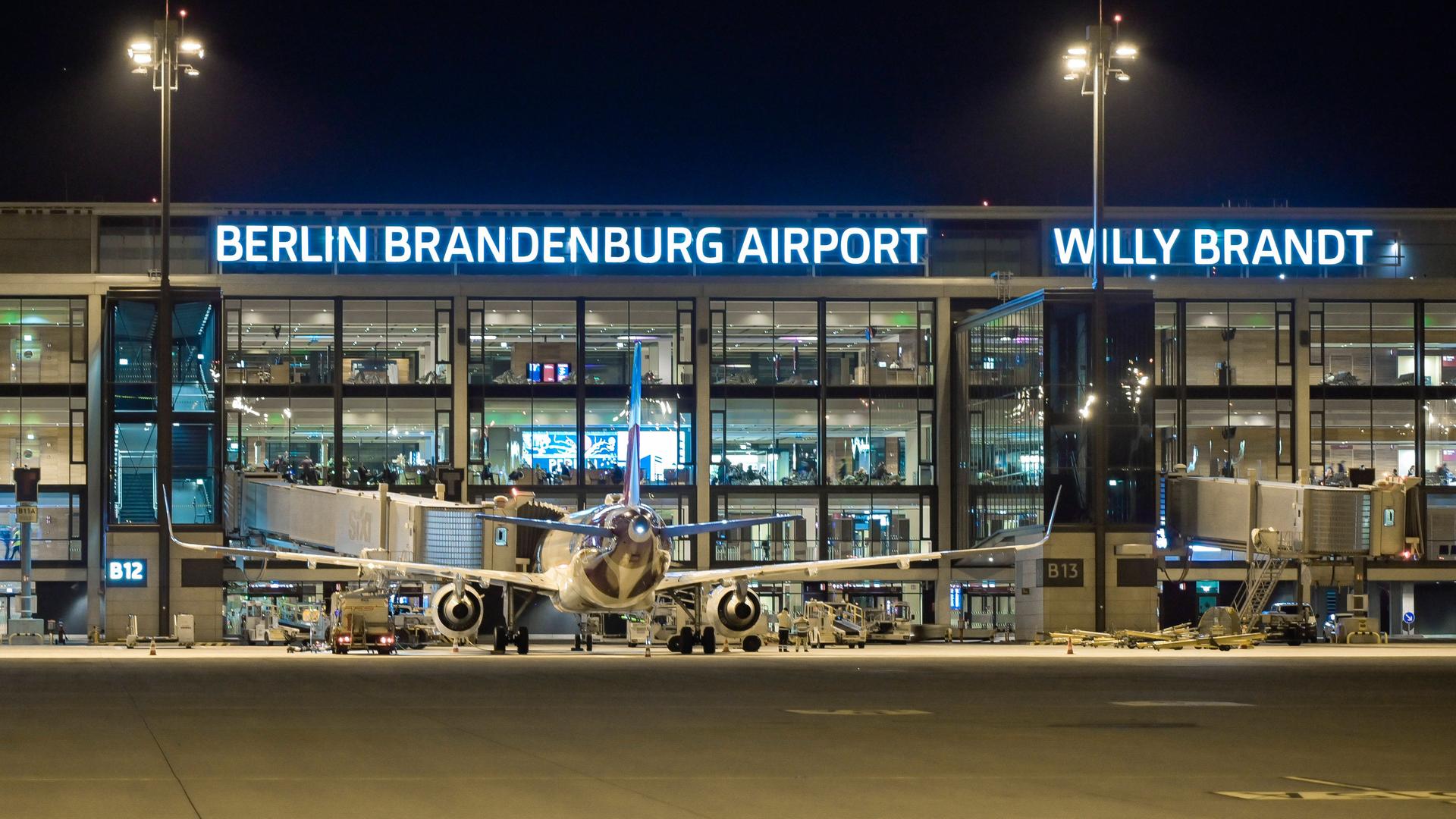 Das Bild zeigt eine Nachtaufnahme des Flughafens. Vor einem Terminalgebäude steht ein Flugzeug.