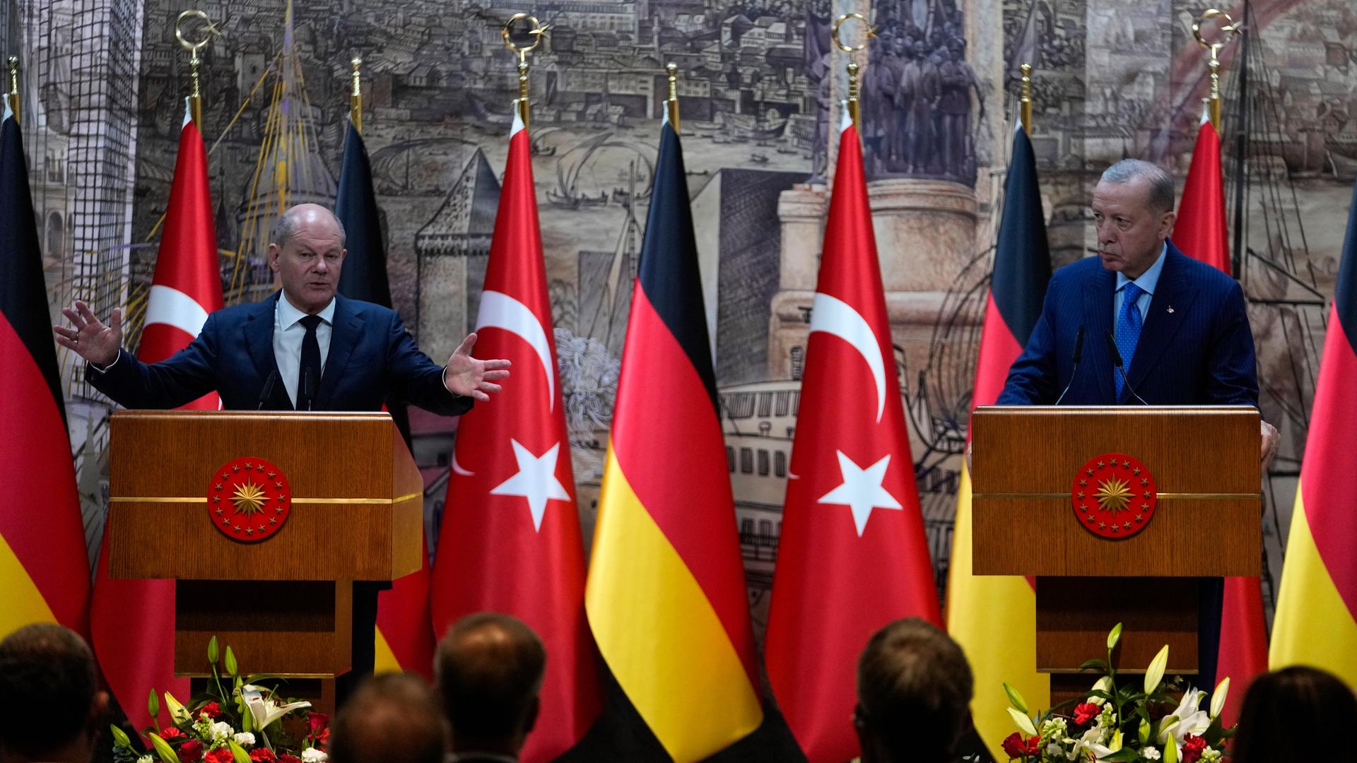 Bundeskanzler Scholz (l.) zu Besuch bei dem türkischen Präsidenten Erdogan in Istanbul. Beide Politiker stehen an einem Rednerpult, hinter ihnen die Flaggen der jeweiligen Länder. 