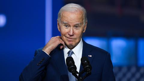US-Präsident Joe Biden steht auf einer Bühne und schaut skeptisch in die Kamera.