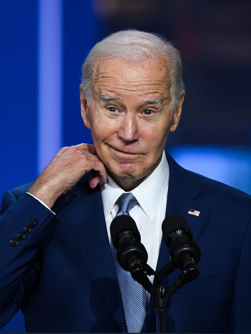 US-Präsident Joe Biden steht auf einer Bühne und schaut skeptisch in die Kamera.
