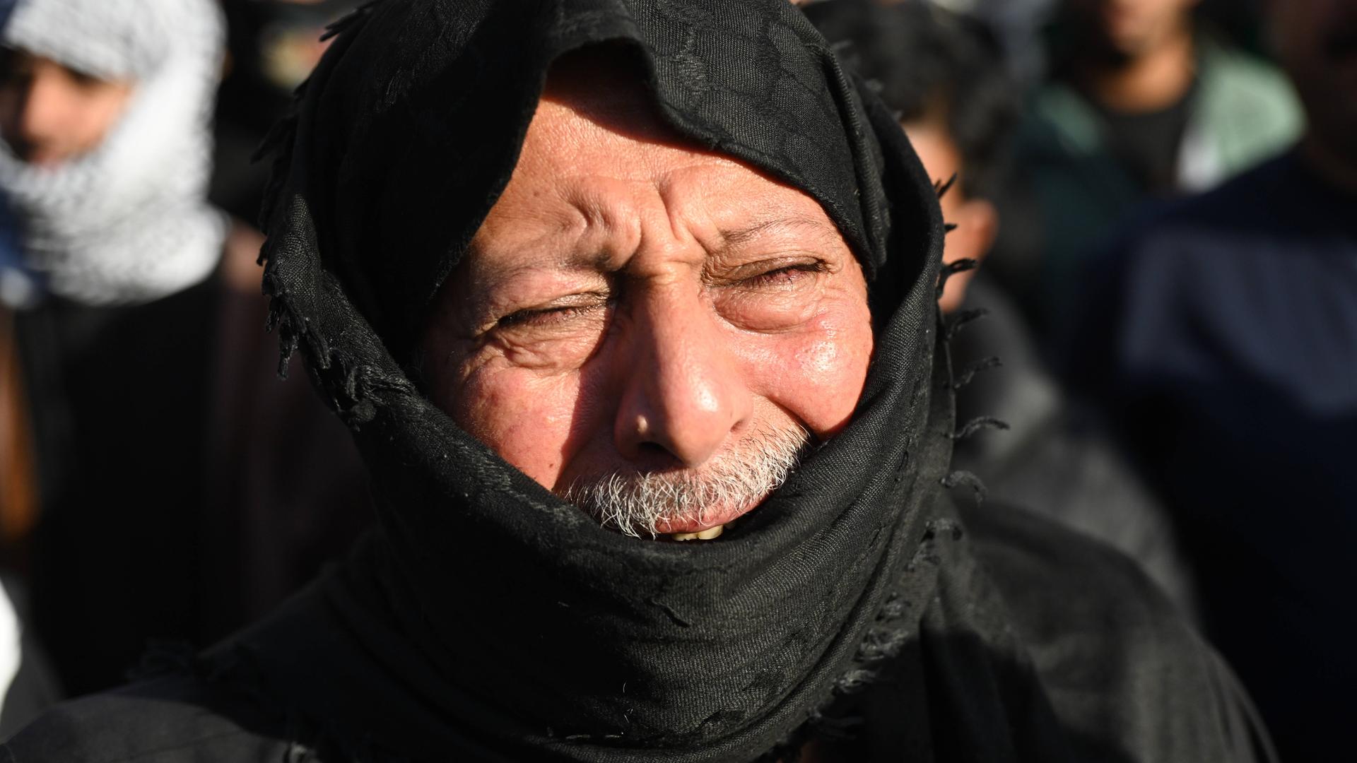 Ein Mann trauert nach dem Tod des iranischen Führers Ali Chameinei. Sein Gesicht ist schmerzverzerrt, es ist von einem schwarzen Tuch verhüllt. 