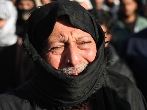 Ein Mann trauert nach dem Tod des iranischen Führers Ali Chameinei. Sein Gesicht ist schmerzverzerrt, es ist von einem schwarzen Tuch verhüllt. 