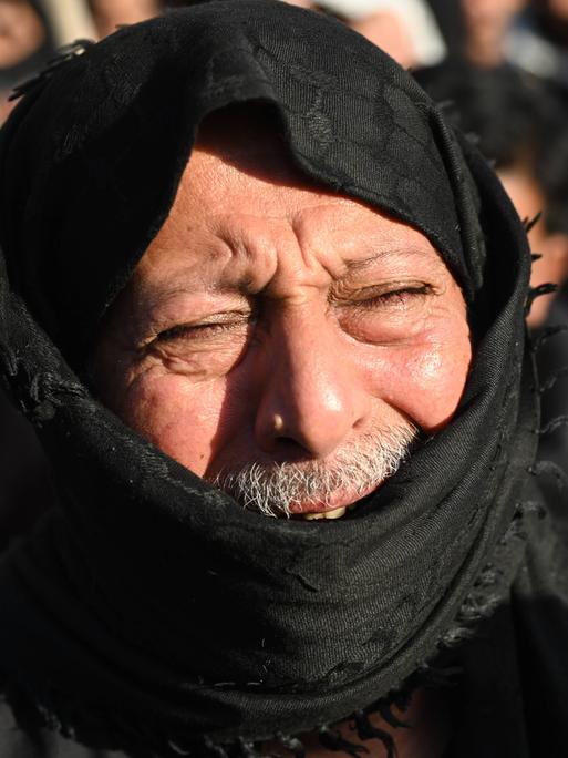 Ein Mann trauert nach dem Tod des iranischen Führers Ali Chameinei. Sein Gesicht ist schmerzverzerrt, es ist von einem schwarzen Tuch verhüllt. 