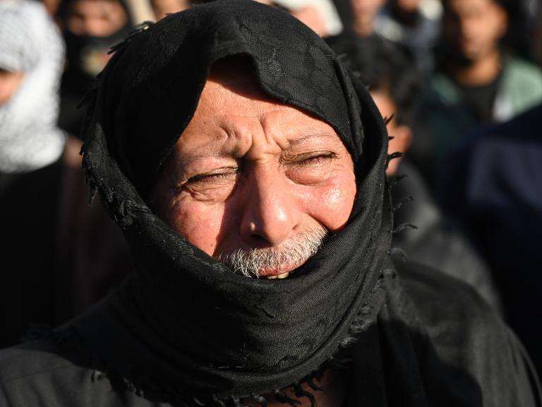 Ein Mann trauert nach dem Tod des iranischen Führers Ali Chameinei. Sein Gesicht ist schmerzverzerrt, es ist von einem schwarzen Tuch verhüllt. 