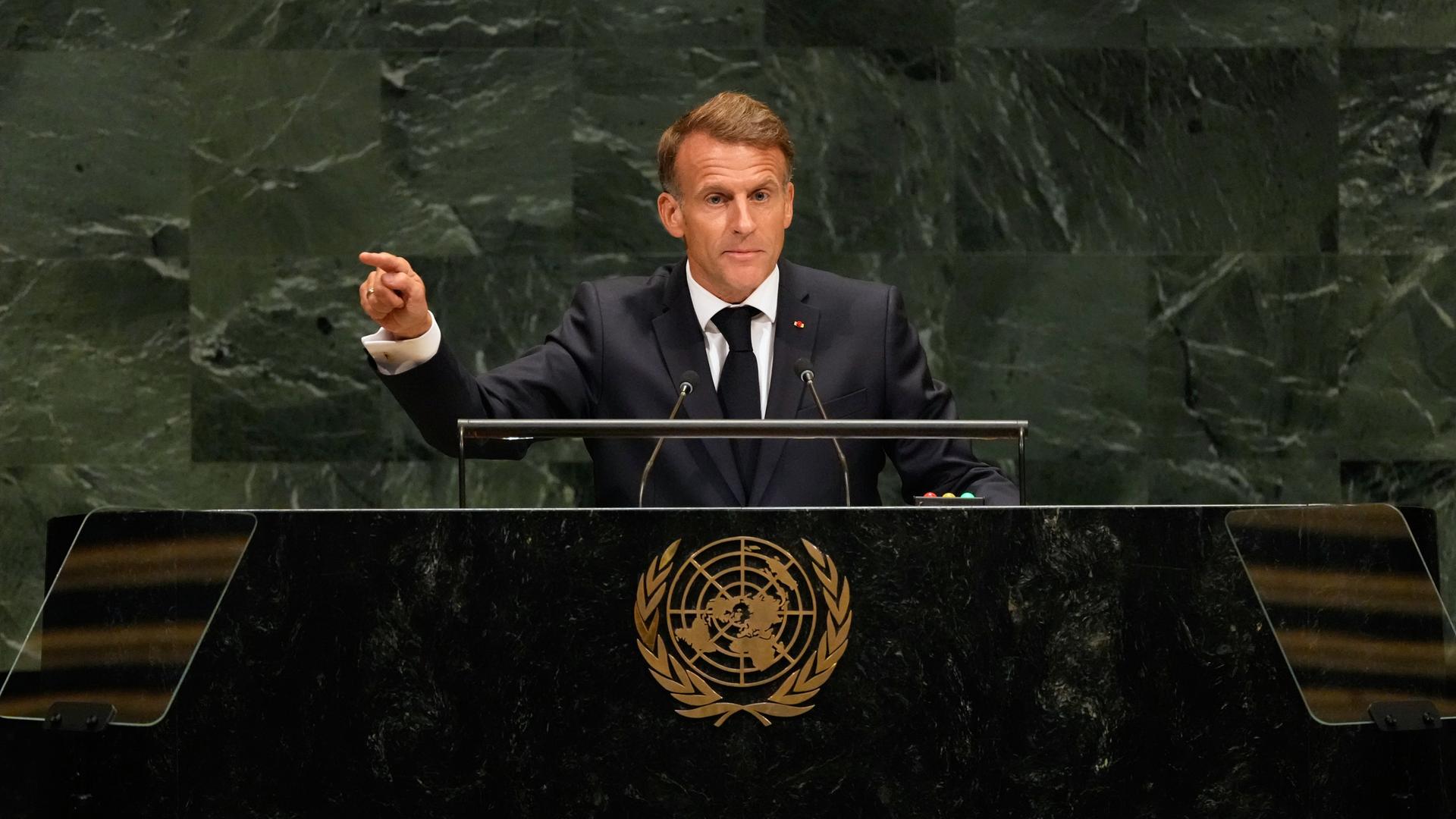 Der französische Präsident Emmanuel Macron steht am Rednerpult und gestikuliert. 