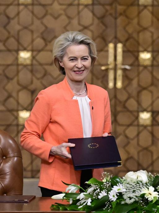 Die Präsidentin der Europäischen Kommission Ursula von der Leyen und der ägyptische Präsident Abdel Fattah al-Sisi bei einem diplomatischen Treffen. Sie halten jeweils eine Mappe in Richtung Kamera. Auf der einen ist das Staatswappen Ägyptens, auf der anderen der Sternenkranz der EU zu sehen.