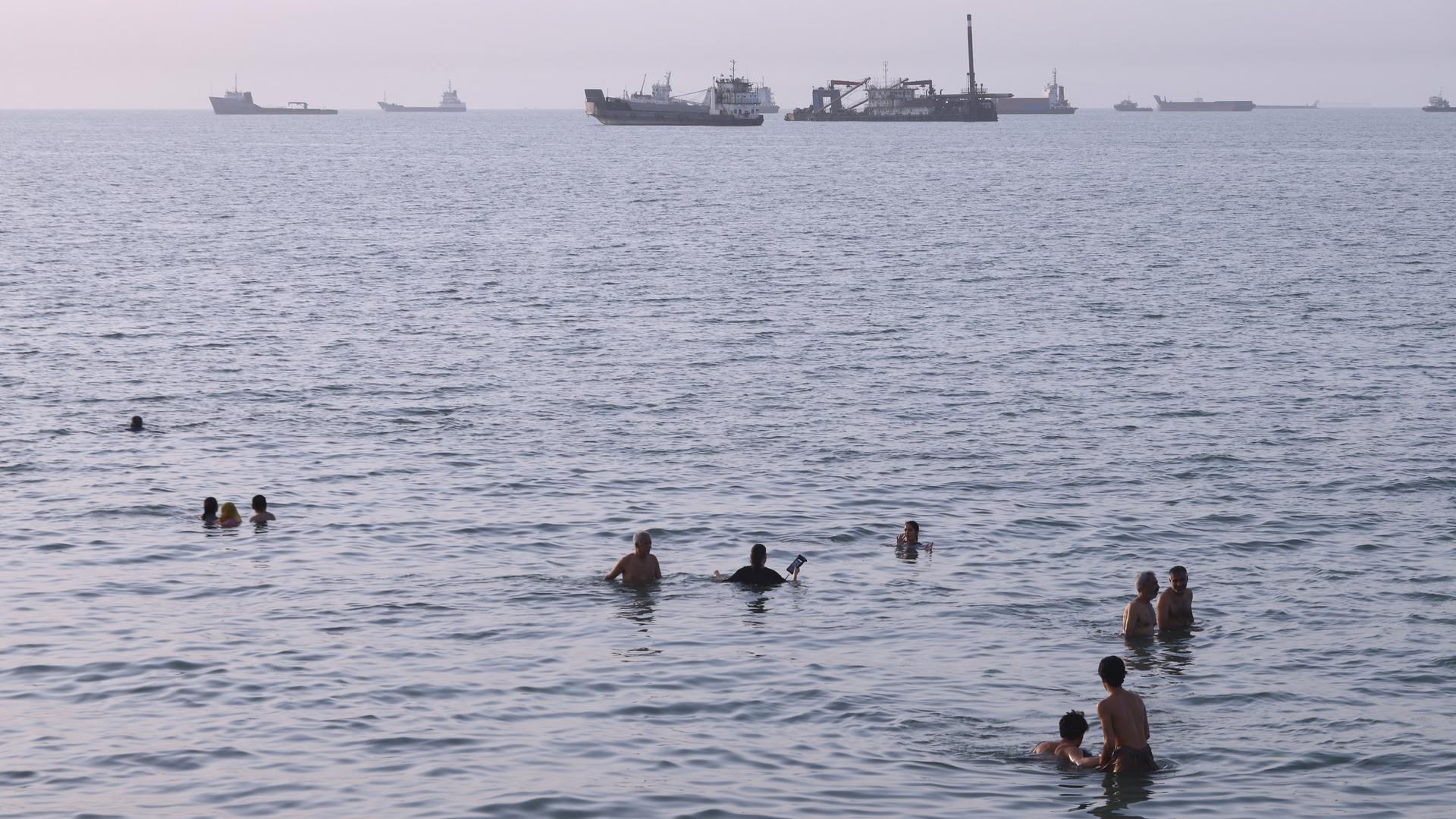 Anwohner schwimmen, während Fracht- und Handelsschiffe in der Straße von Hormus vor Bandar Abbas im Iran vor Anker liegen. Anwohner schwimmen, während Fracht- und Handelsschiffe in der Straße von Hormus vor Bandar Abbas im Iran vor Anker liegen.
