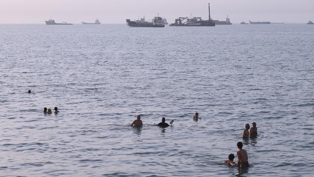 Anwohner schwimmen, während Fracht- und Handelsschiffe in der Straße von Hormus vor Bandar Abbas im Iran vor Anker liegen. 
