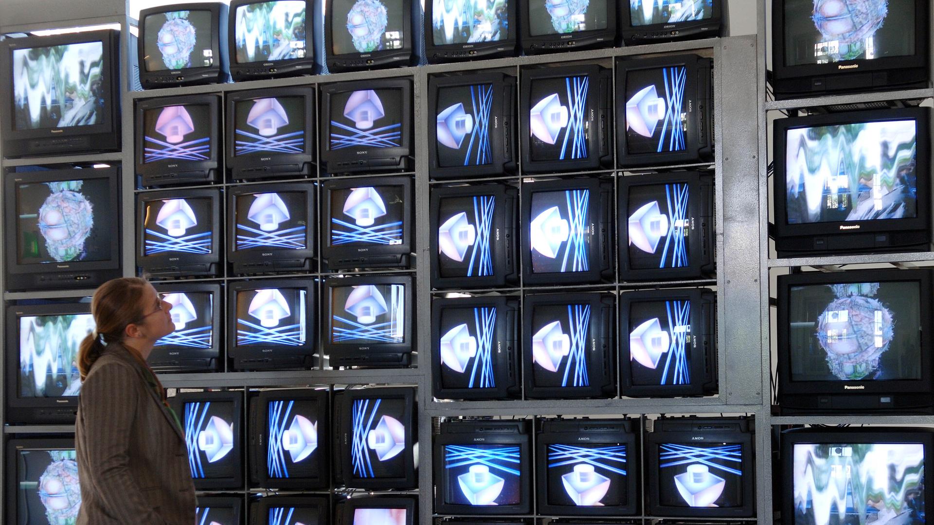 In der Bauhaus-Universität in Weimar betrachtet eine junge Frau im Jahr 2005 die Videowand "Internet Dream" von Nam June Paik. Die Wand besteht aus 52 Monitoren, die sowohl unterschiedliche Einzelbilder als auch ein großes Ganzes zeigen. 