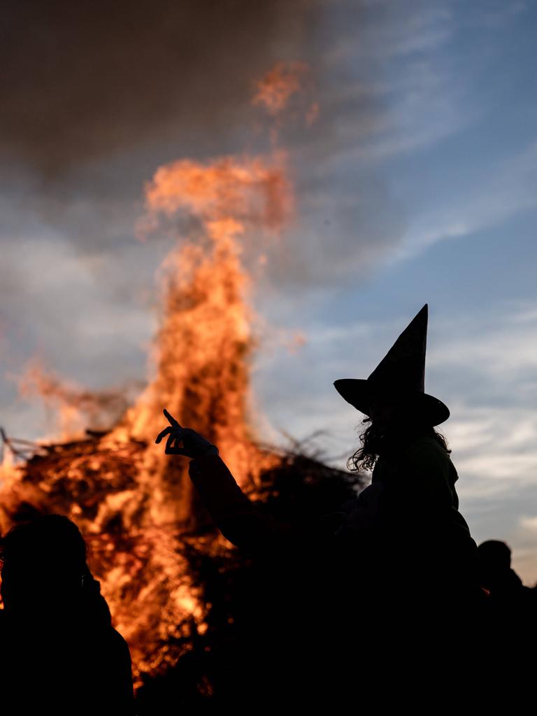 Eine Person als Hexe mit einem Hexenhut zeichnet sich als Silhouette vor einem traditionellen Feuer zur Walpurgisnacht ab
