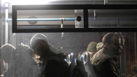 Kriegsgefangene sitzen mit ernsten Minen in einem Bus der russischen Armee.