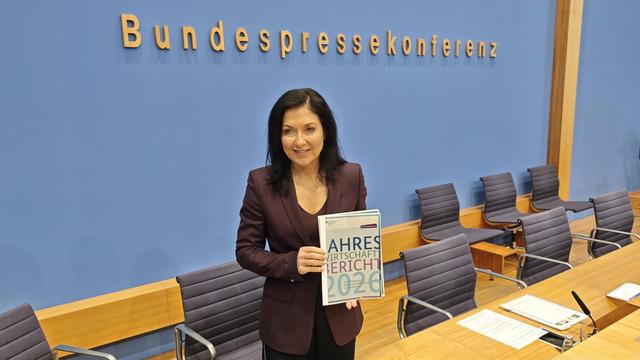 Bundewirtschaftsministerin Katherina Reiche hält den Jahreswirtschaftsbericht der Bundesregierung in den Händen. Sie steht vor dem blauen Hintergrund der Bundespressekonferenz.