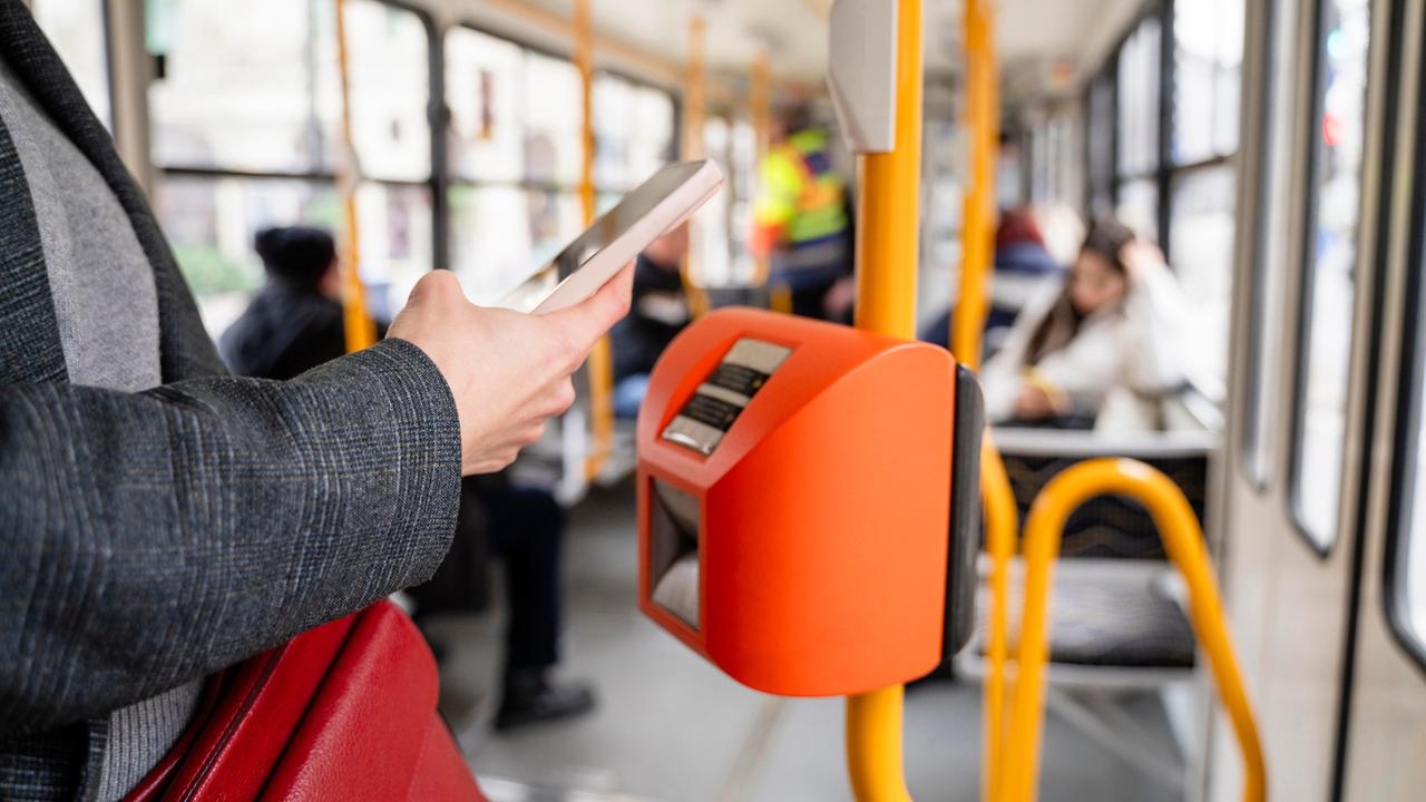 Eine Person bezahlt mit dem Smartphone in einer Straßenbahn.