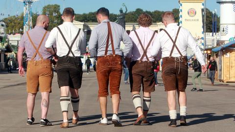 Auftakt zum Oktoberfest in München, Bayern, Deutschland: Männer in Lederhosen spazieren über das Festgelände vor der Bavaria.
