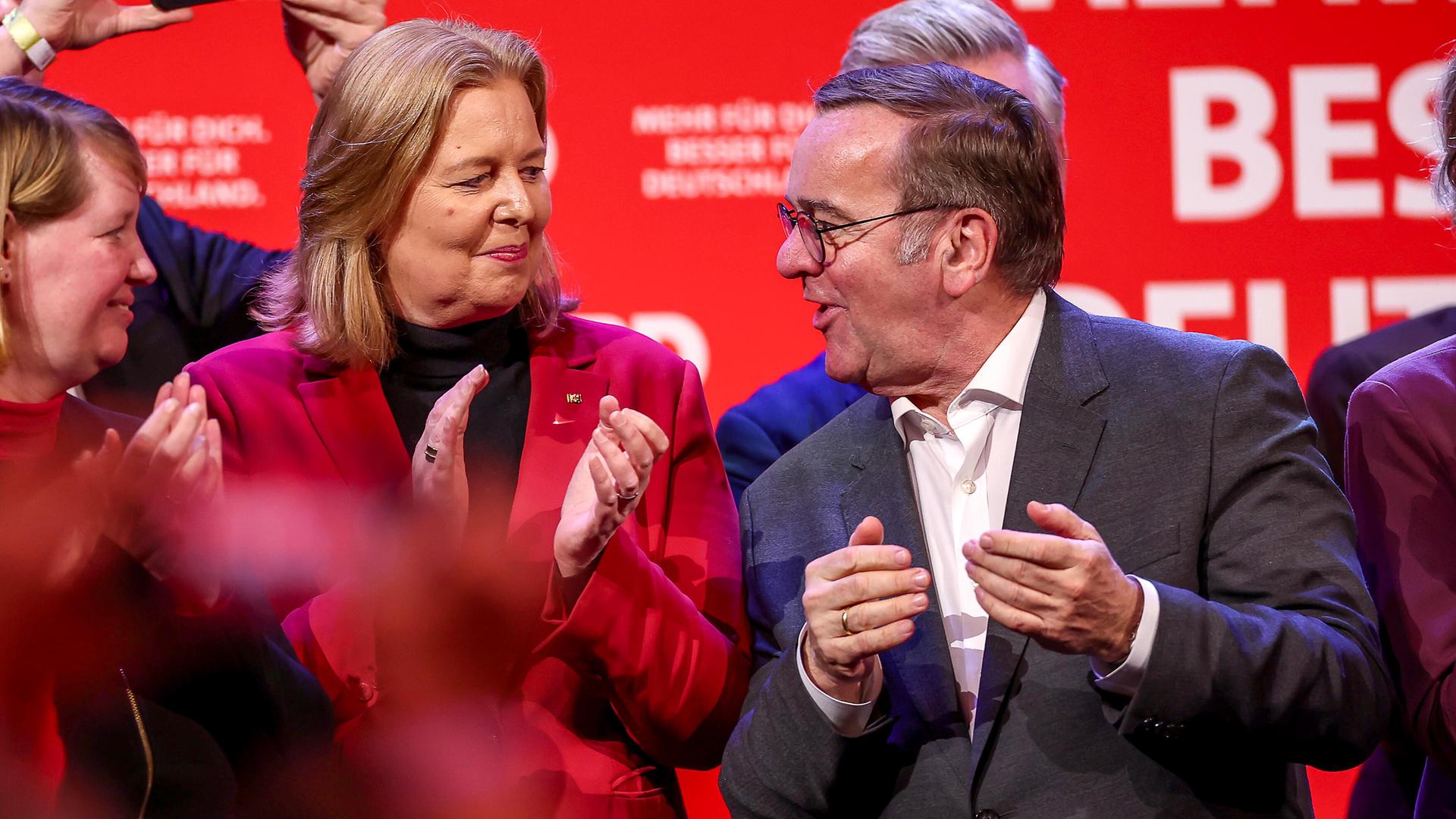 Bärbel Bas steht neben Boris Pistorius auf einer SPD-Wahlveranstaltung in Dortmund. Beide schauen sich an und klatschen in die Hände. 
