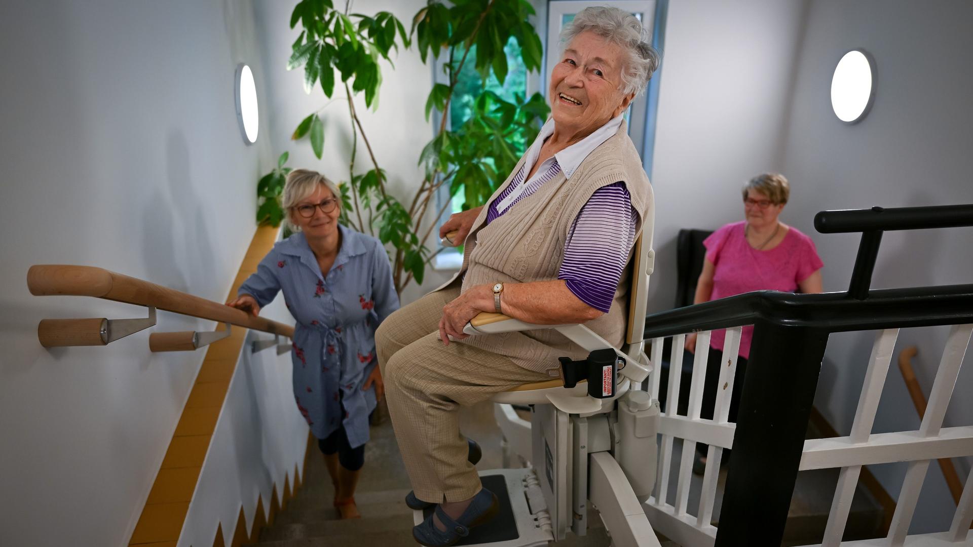 Eine ältere Frau sitzt in einem Treppenlift Eine ältere Frau sitzt in einem Treppenlift