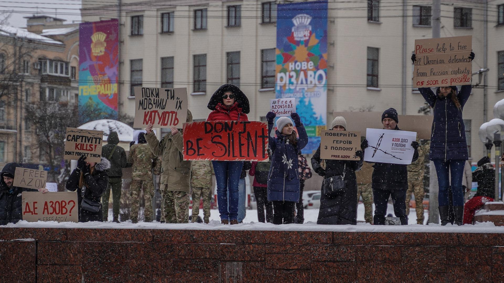 Menschen in Kiew halten Protestschilder in die Höhe, auf eienm steht "Don't be silent"