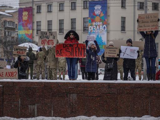 Menschen in Kiew halten Protestschilder in die Höhe, auf eienm steht "Don't be silent"