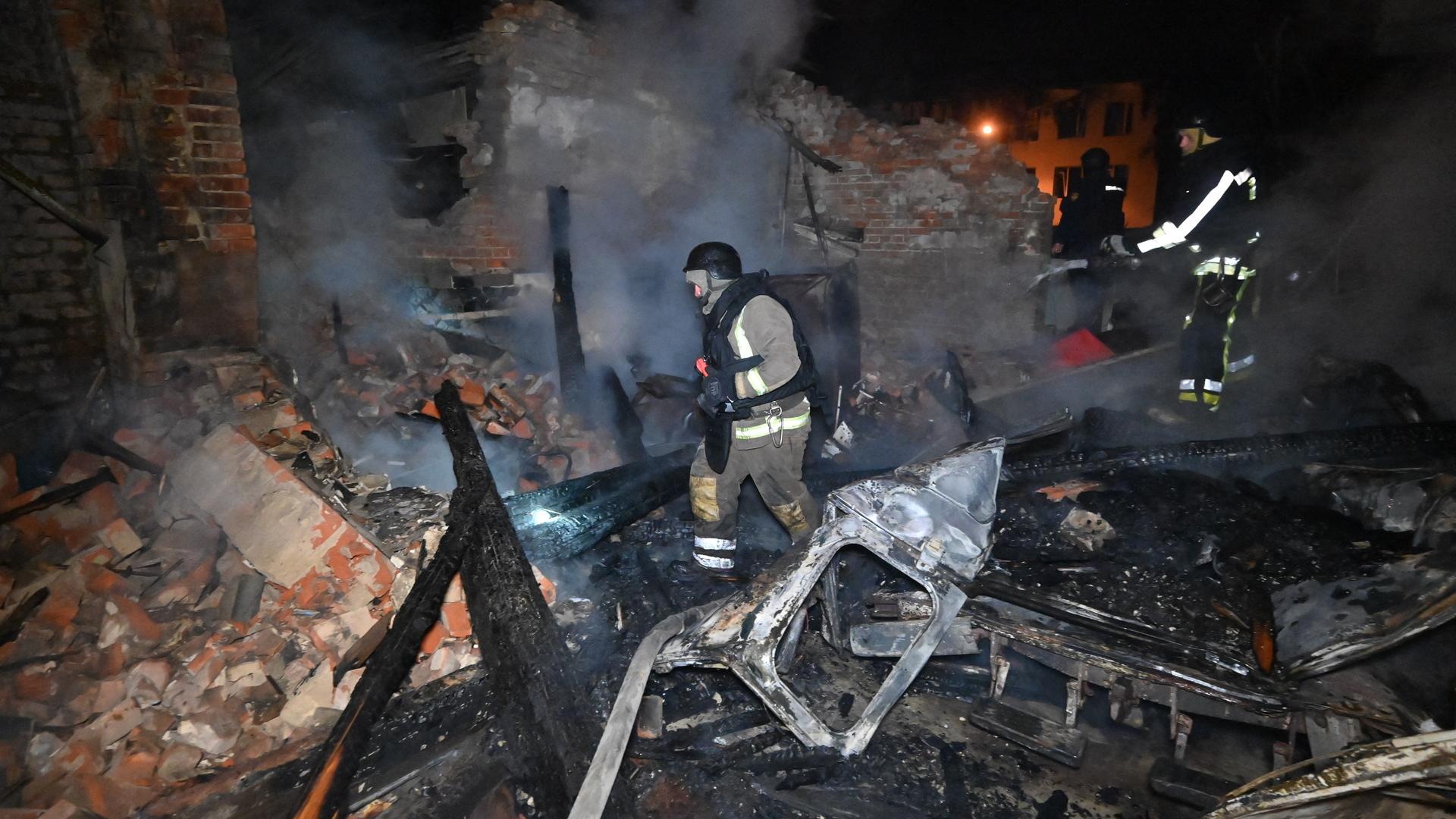 Ukrainische Feuerwehrleute löschen einen Brandan einem zerstörten Haus nach einem russischen Angriff.