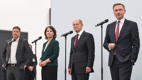 Robert Habeck, Annalena Baerbock, Olaf Scholz und Christian Lindner stehen während einer Pressekonferenz am Mikrofon.