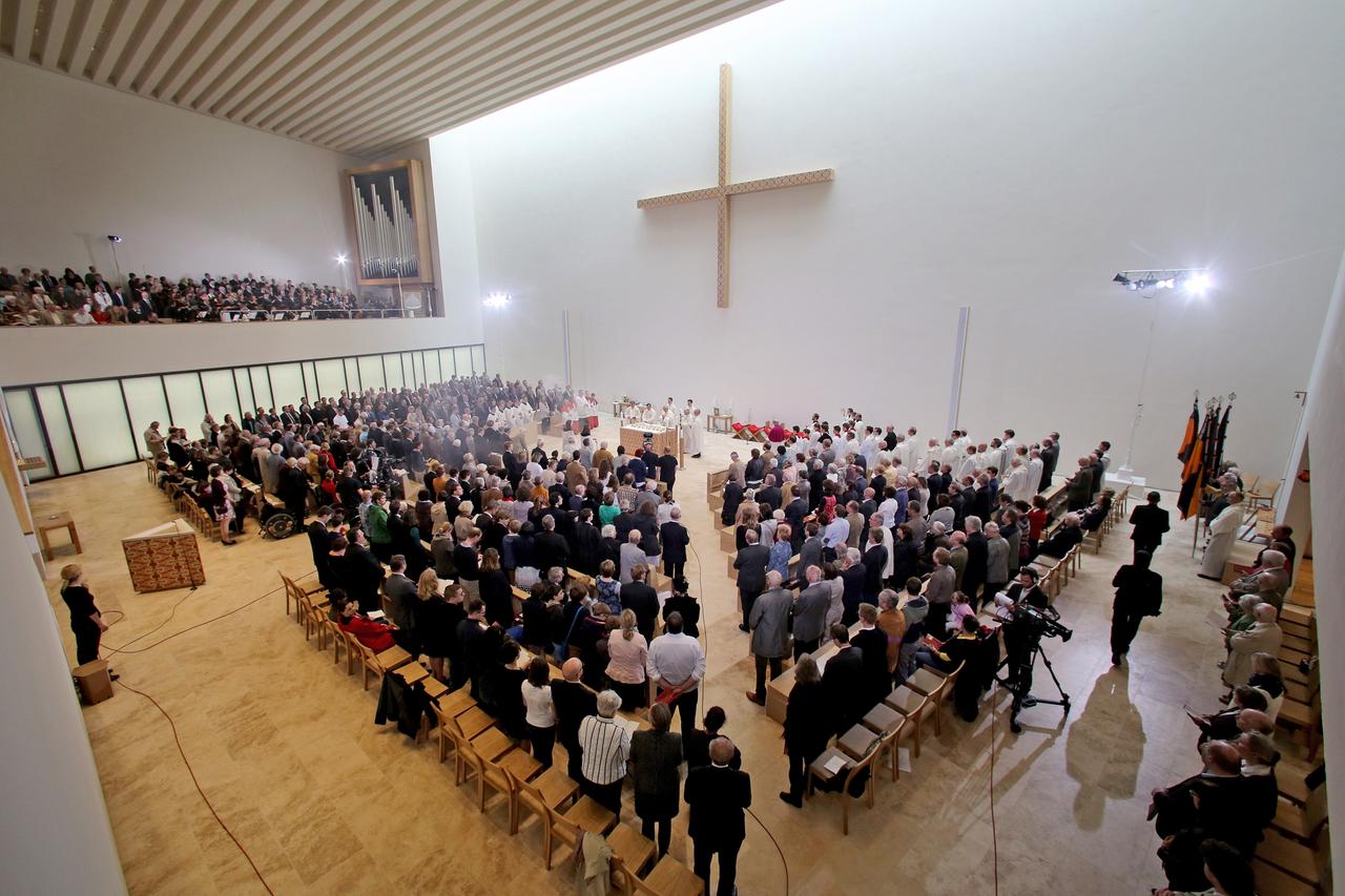 Die Gemeinde steht unter dem Kreuz im schlichten Innenraum der neuen Probsteikirche in Leipzig.