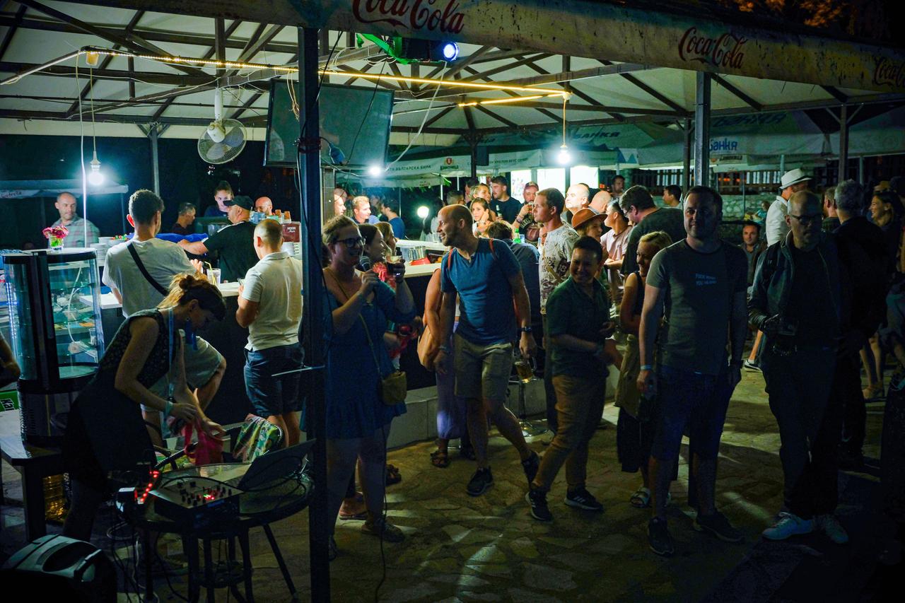 Karaoke am letzten Abend beim Bansko Nomad Fest. Menschen stehen um eine Bar versammelt.