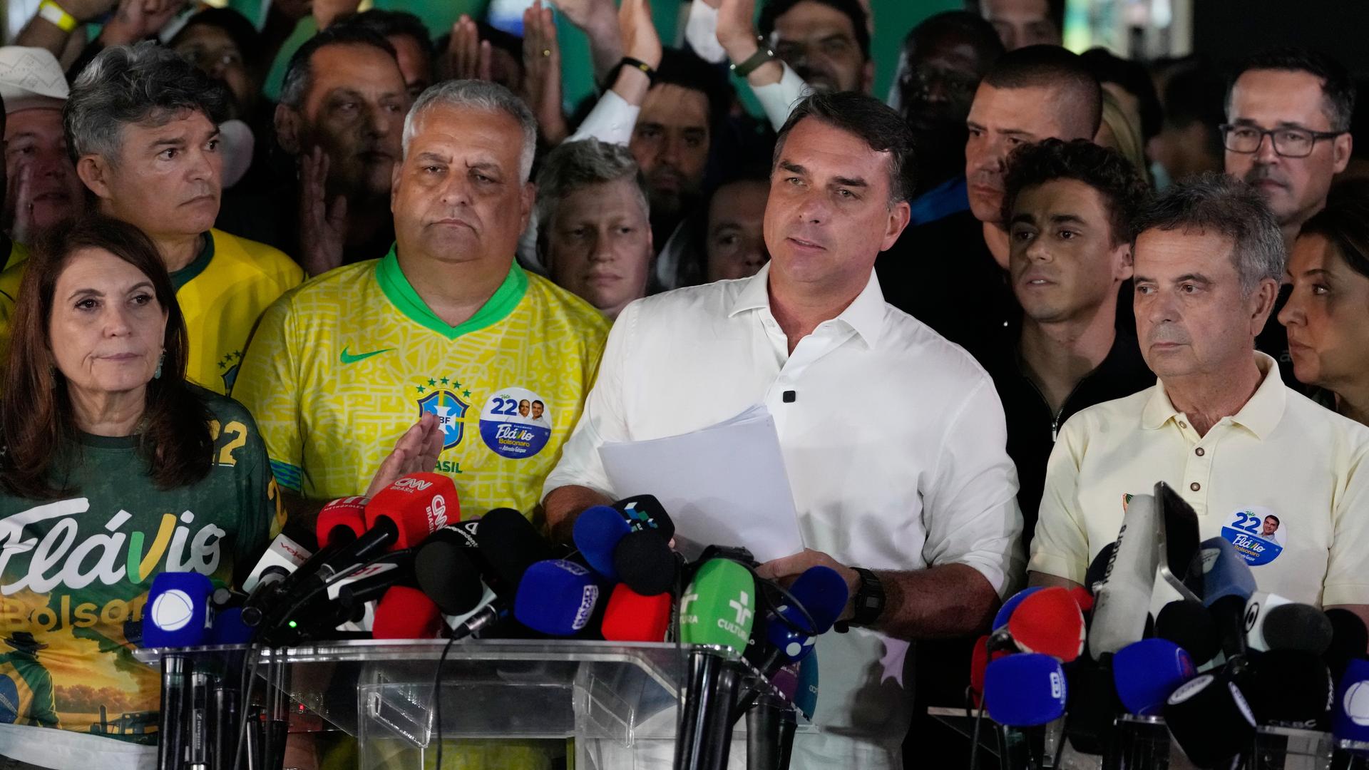 Der brasilianische Präsidentschaftskandidat Flavio Bolsonaro spricht nach der Stichwahl. Dabei ist er umringt von mehreren Personen. Der brasilianische Präsidentschaftskandidat Flavio Bolsonaro spricht nach der Stichwahl. Dabei ist er umringt von mehreren Personen.